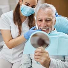 Patient with dentures in Spring smiling while looking in mirror