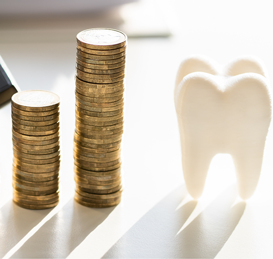 Model of a tooth next to two stacks of coins