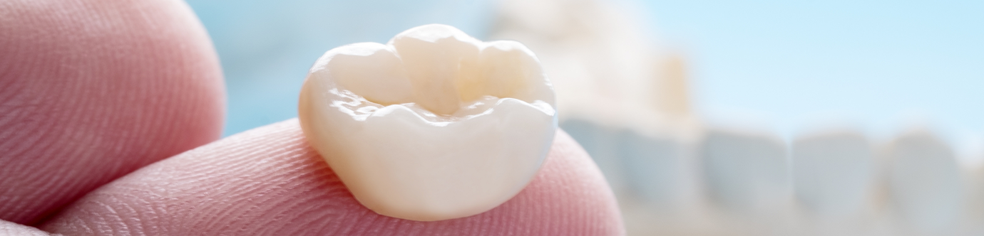 A dental crown resting on a person's finger