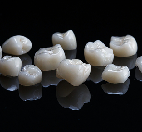 Several white dental crowns against a black background