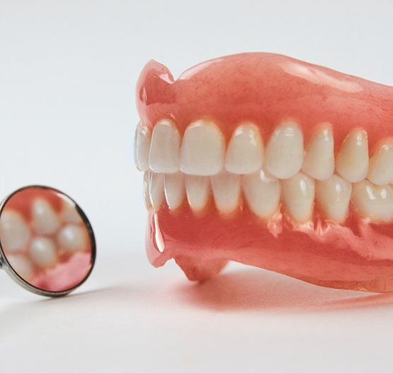 Dental mirror next to a set of full dentures