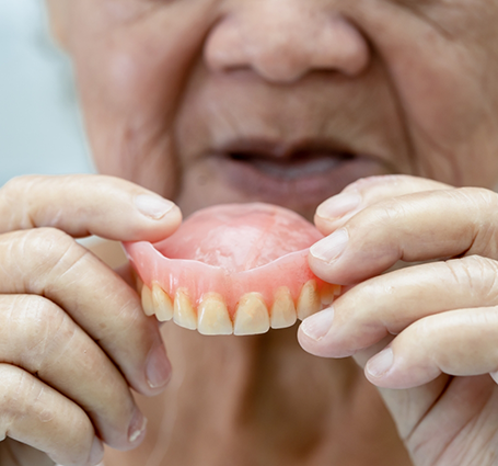 Senior holding a full denture