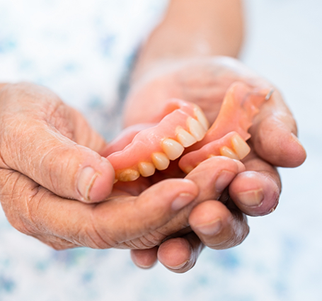 Hands holding a set of full dentures