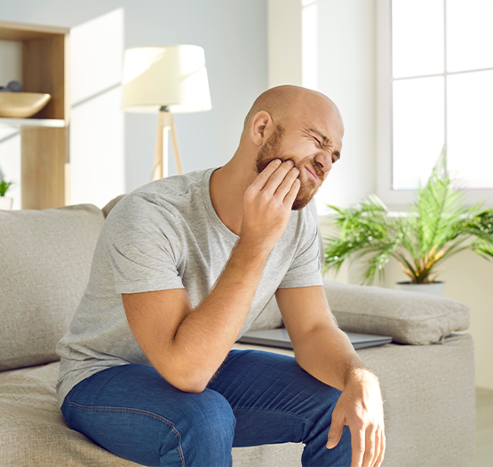 Man wincing in pain and touching his cheek