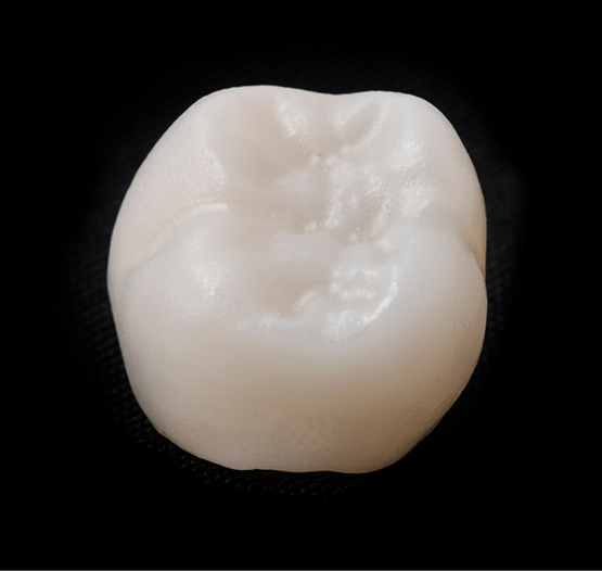 Tooth colored dental crown against a black background