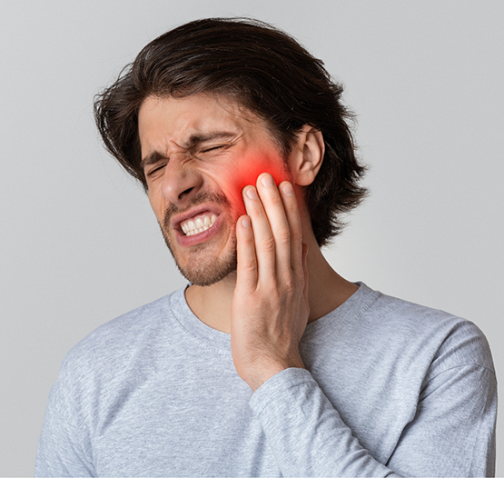Man wincing in pain and touching his cheek