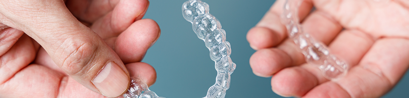 Hands holding two clear orthodontic aligners