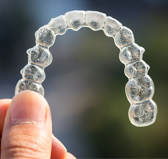 Hand holding a clear aligner