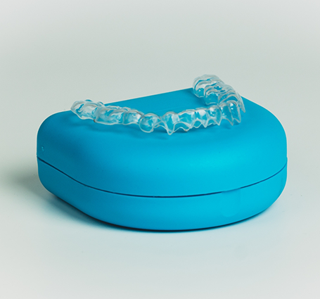 Clear aligner atop its blue storage case
