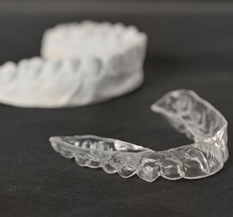 Clear aligner next to a model of the teeth