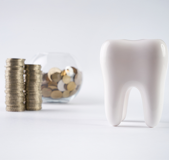 Model of a tooth next to a jar filled with coins