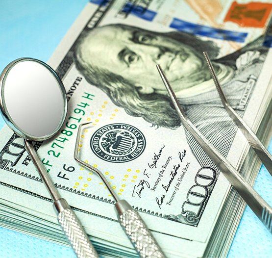 Dental instruments on top of hundred dollar bills
