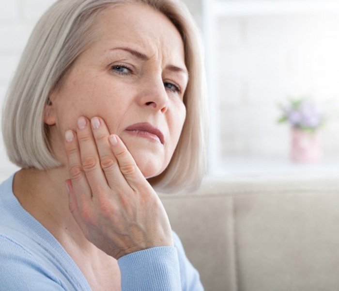 a woman touching her jaw due to tooth pain