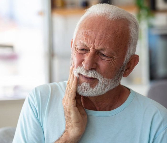 a man touching his cheek due to tooth pain