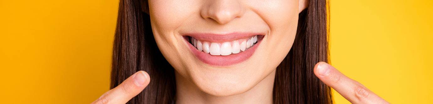 Woman pointing to her flawless smile with veneers in Spring