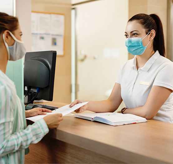 Dental office receptionist handing paperwork to a patient